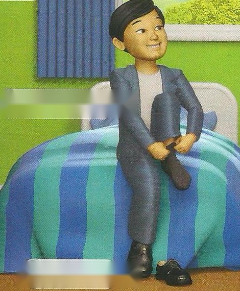 A boy in a grey jacket sitting on a bed with blue and green stripes