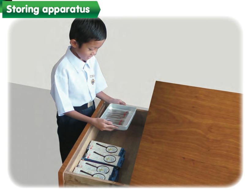 A pupil puts a tray of apparatus into a drawer