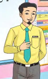 Seorang guru lelaki berbaju kuning berdiri di dalam kelas