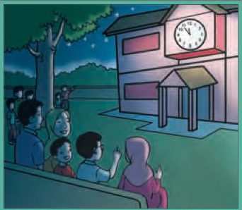 Satu keluarga duduk di padang pada waktu malam dan menunggu di hadapan bangunan yang ada jam besar