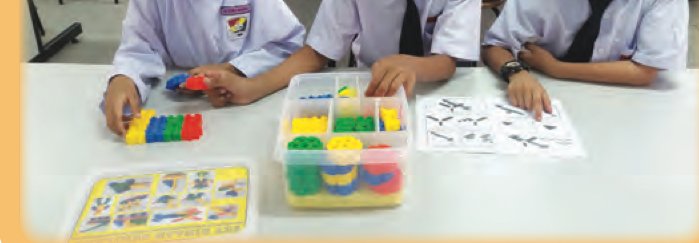Meja dengan kotak komponen, manual bergambar dan beberapa komponen yang telah dikeluarkan