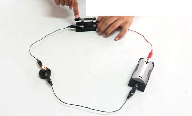 A circuit with a dry cell, a switch and a bulb that is lit
