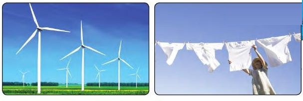 Wind turbines turning in a field, and white clothes drying on a clothes line