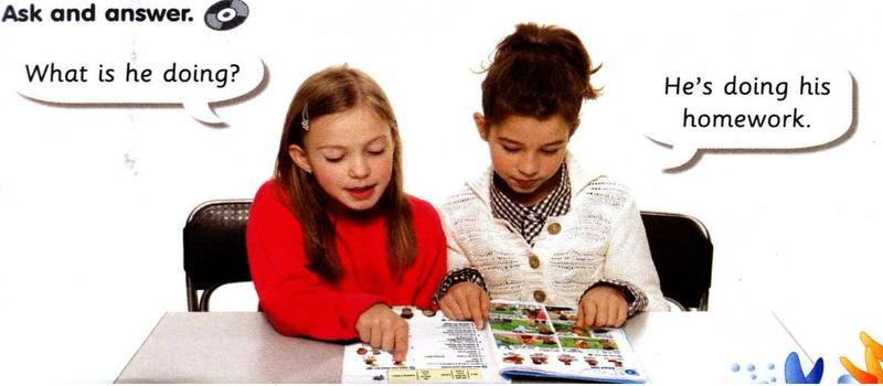 Two children look at a book. One asks: What is he doing? The other says: He's doing his homework.