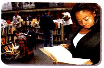 A girl reads a book in a library with many bookshelves