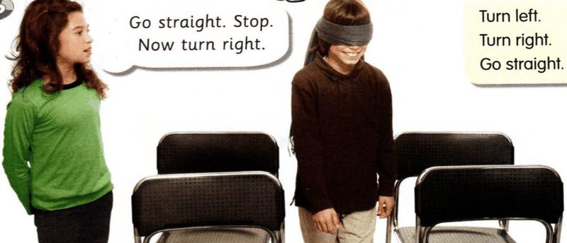 A girl gives directions to a boy with a blindfold who walks between chairs