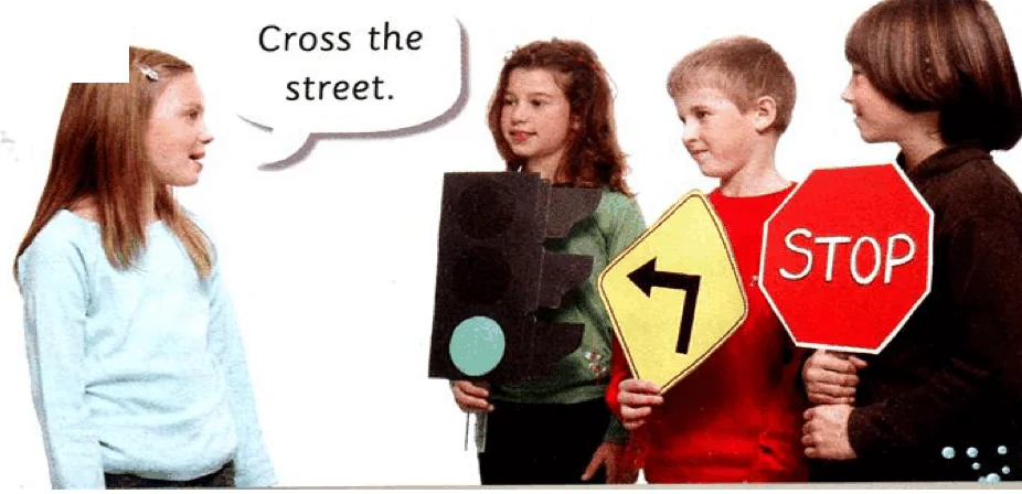 Children hold a traffic light, a turn-left sign and a STOP sign. A girl says Cross the street.