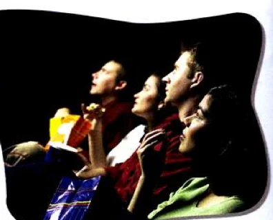 A family watching a film and eating popcorn in a dark cinema
