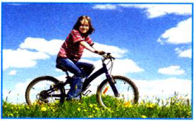 A girl riding a bike on a grassy hill