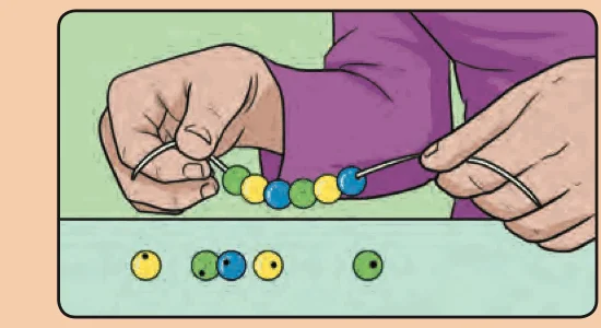 A hand threading beads of different colours