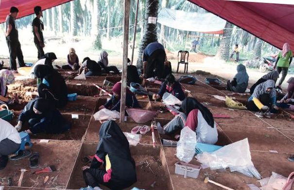 Sekumpulan pengkaji sedang menggali petak-petak tanah di bawah khemah di sebuah tapak