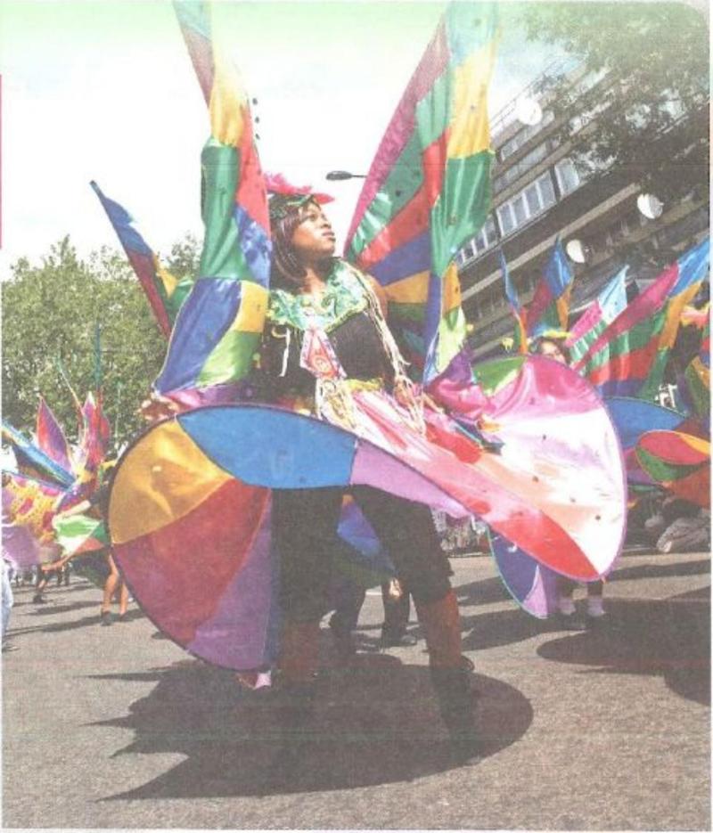 A person in a huge colourful costume with bright wings at a street carnival