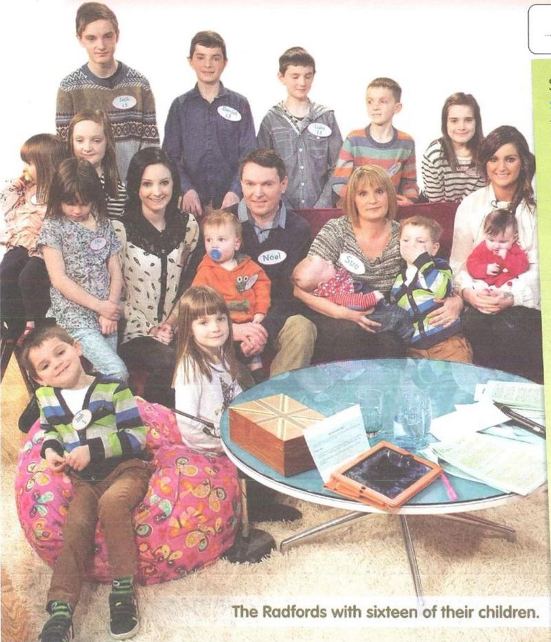 Sue and Noel Radford sitting with sixteen of their children in a living room