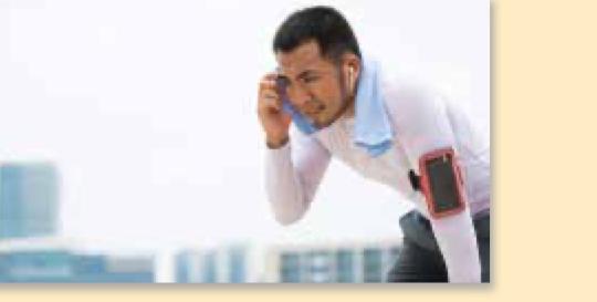 A man bent over with a towel round his neck, catching his breath after exercise