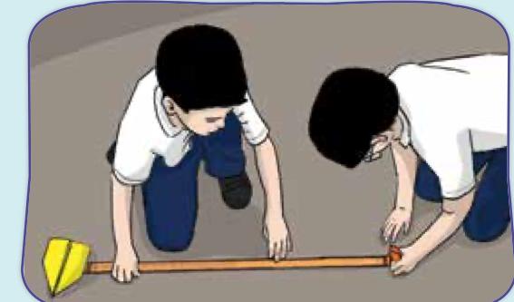 Two pupils measuring the distance of a paper plane on the floor with a measuring tape