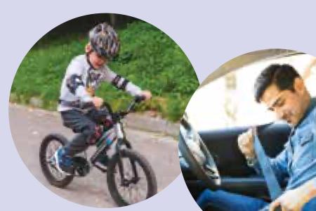 A boy wearing a helmet on a bicycle and a man wearing a seat belt in a car