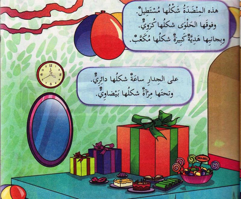 Meja kedua dengan hadiah kubus besar, gula-gula dan jam dinding bulat serta cermin bujur, dengan dua kotak teks Arab