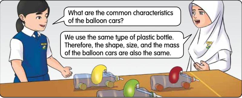Three balloon cars with yellow, green and red balloons on a table and two pupils talking