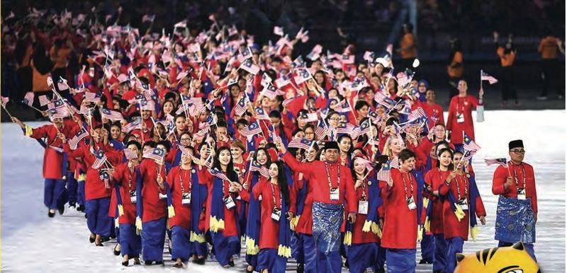 Atlet Malaysia berbaju merah dan biru membawa bendera semasa upacara pembukaan