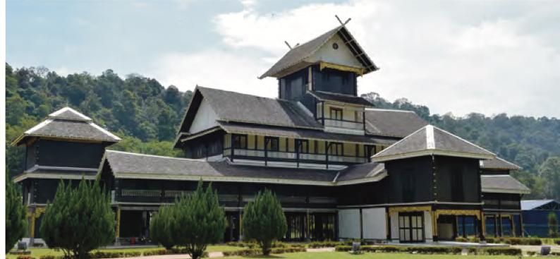 Istana kayu bertingkat berwarna hitam dengan bumbung curam di kawasan berbukit