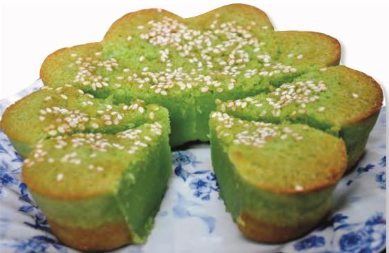 Kuih bakar kemboja berwarna hijau ditabur bijan di atas pinggan