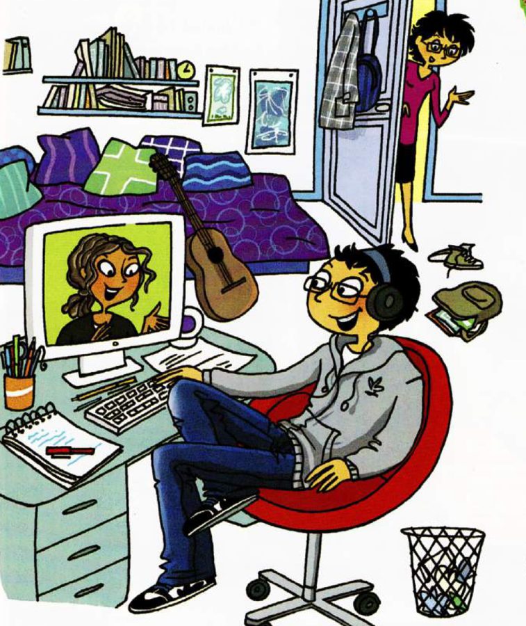 A boy with headphones chats to a girl on his computer screen while his mother looks in at the bedroom door