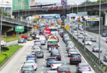 Foto sebatang lebuh raya yang sesak dengan kereta, lori dan bas bergerak perlahan sebelum sebuah jejantas