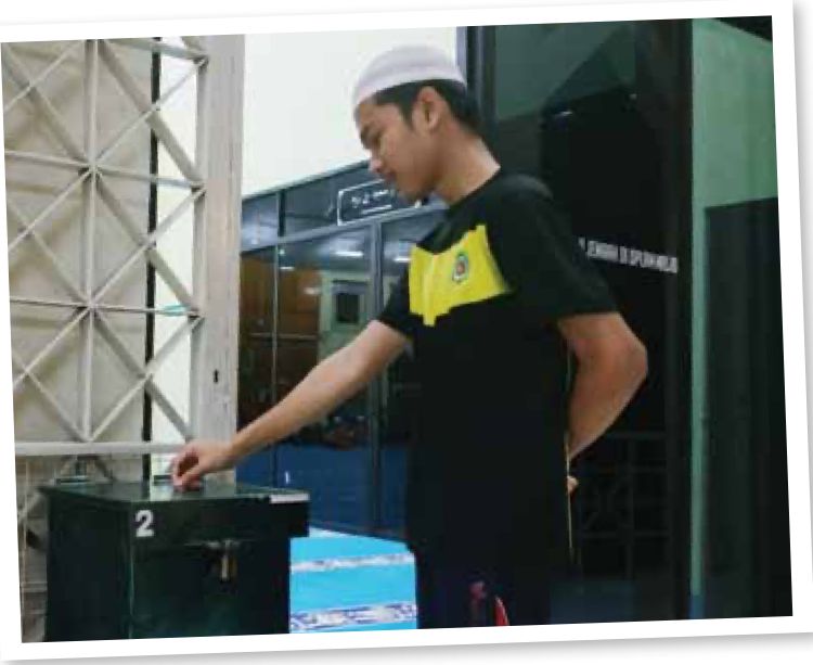 Seorang remaja lelaki memasukkan wang ke dalam tabung di masjid
