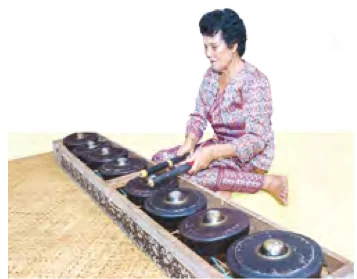 Seorang wanita memukul engkerumong, deretan gong kecil di atas bingkai kayu