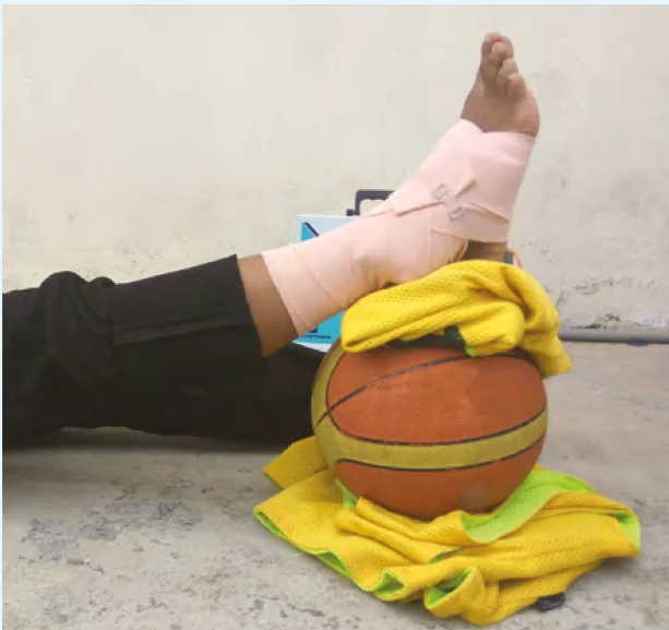 Kaki berbalut diletakkan di atas bola keranjang dan baju sebagai sokongan