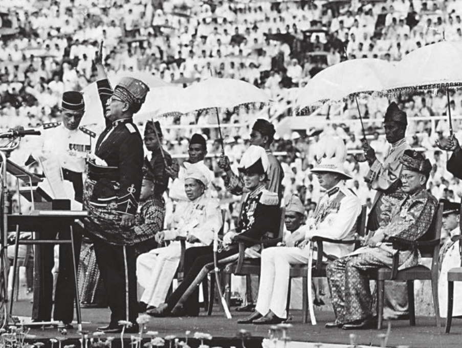 Gambar 1: Tunku Abdul Rahman mengangkat tangan melaungkan Merdeka di Stadium Merdeka dengan Raja-raja Melayu duduk di belakangnya