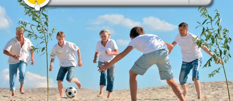 Grandparents, parents and children playing football together on a sandy field